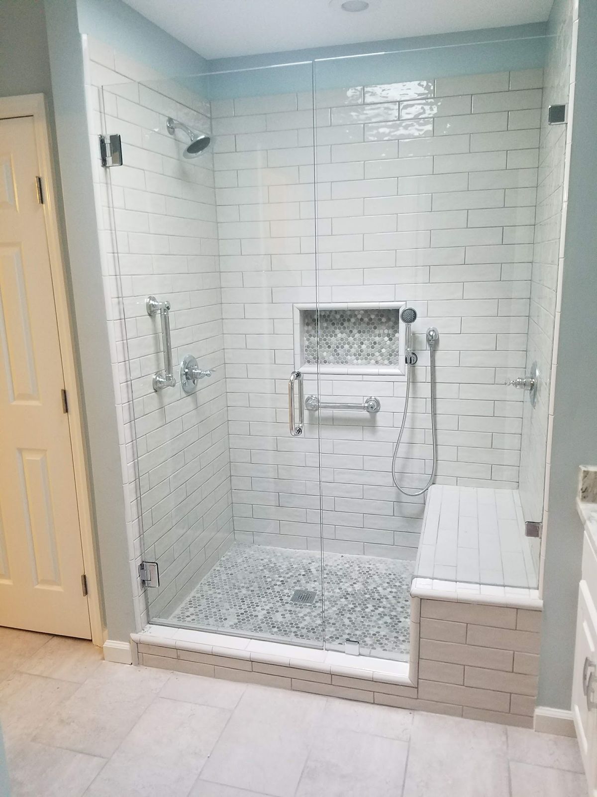 Tiled walk-in shower with glass door and bench